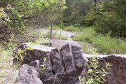 View of CCC Quarry with stone bearing rock drill marks in foreground.