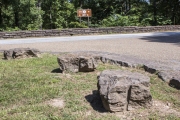 Boulders with rock drill marks lining roadway.