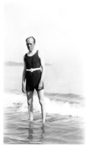 John Gould Fletcher, standing on shoreline in bathing suit, circa 1923