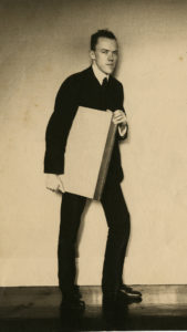 John Gould Fletcher, standing with portfolio, circa 1912