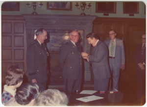 General Joseph R. Chappell, Max Howell, Dale Bumpers, and Clarence Bell are standing sharing a candid moment as Bumpers pins a star on Howell during his promotion to general of the Arkansas National Guard. 