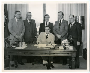 Max Howell, second from left, joins four men to watch Governor David Pryor sign a bill into law.