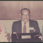 Christophe stands at a podium and addresses a Dunbar alumni reunion in 1974