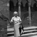 Huckaby stands in front of the iconic entrance to Central High School with students sitting overhead.