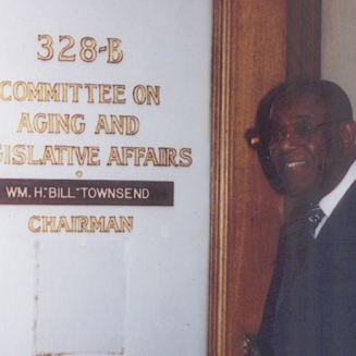Dr. Townsend in front of the door to the Committee on Aging and Legislative Affairs, ca. 1995