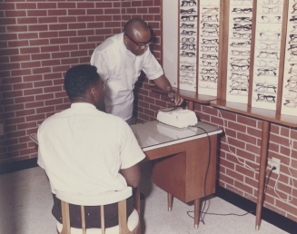 Dr. Townsend helps fit a patient with glasses at his clinic on Wright Ave, early 1980s Dr. Townsend helps fit a patient with glasses at his clinic on Wright Ave, early 1980s