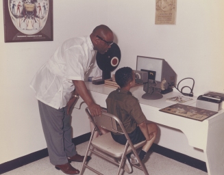Dr. Townsend gives a vision exam to a boy at his clinic on Wright Ave, early 1980s