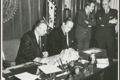 Faubus and unidentified man seated in church hall, possibly Camp Aldersgate meeting