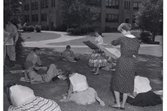 Students sketching Arkansas National Guard troops relaxing on lawn in front of Central High School