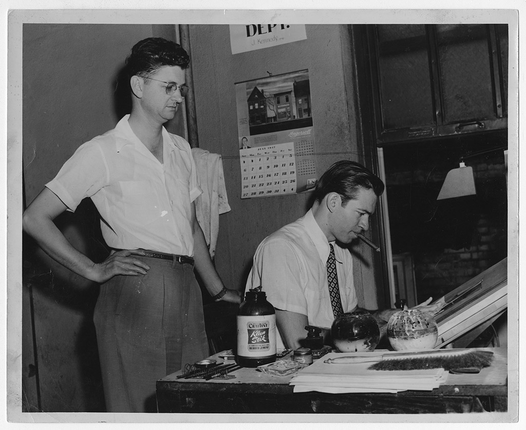 Jon Kennedy draws a cartoon with man watching from behind. Jon Kennedy draws a cartoon with man watching from behind.