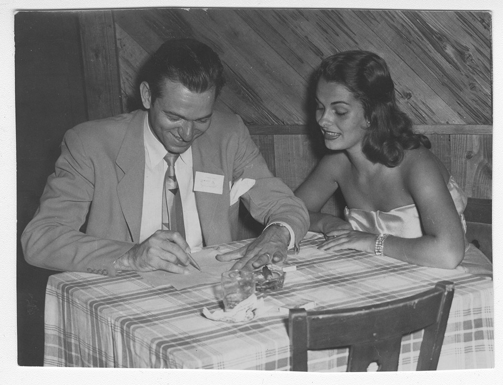 Jon Kennedy sits at a table with Miss America drawing cartoons. Jon Kennedy sits at a table with Miss America drawing cartoons.