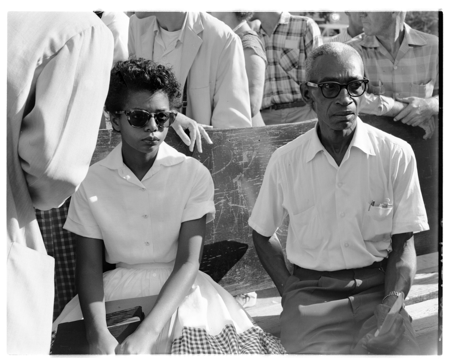 Elizabeth Eckford with Lucius Christopher (L. C.) Bates on bus bench surrounded by protesters. Raymond Preddy photographs on the Little Rock Central High School Crisis, 1957 (UALR.PH.0095)