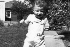 Toddler Jim Guy Tucker walking on sidewalk