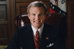 Governor Jim Guy Tucker poses at desk
