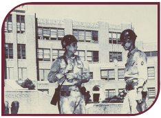 Sepia photograph of two National Guardsmen standing in front of Central High School