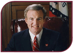 Color photograph of Governor Jim Guy Tucker posing at his desk