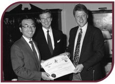 Black and white photograph of Jim Guy Tucker and Bill Clinton presenting a certificate to J. H. Ouyang