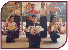 Color photograph of eight young Vietnamese women performing a fan dance in traditional costumes.