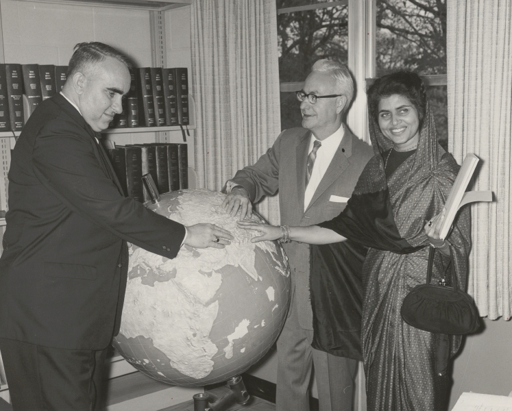 Lou Rives, Roy Kumpe, and an unidentified woman in a sari feeling a raised-relief globe, circa 1960s