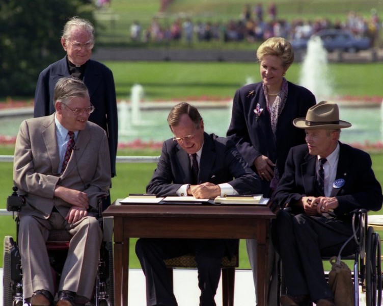 President George H. W. Bush signs the Americans with Disabilities Act in a signing ceremony, 26 July 1990