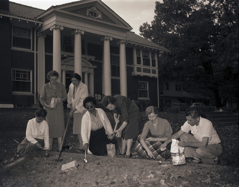 Trainees gardening in front of the Brack Home with garden club women, 28 October 1958